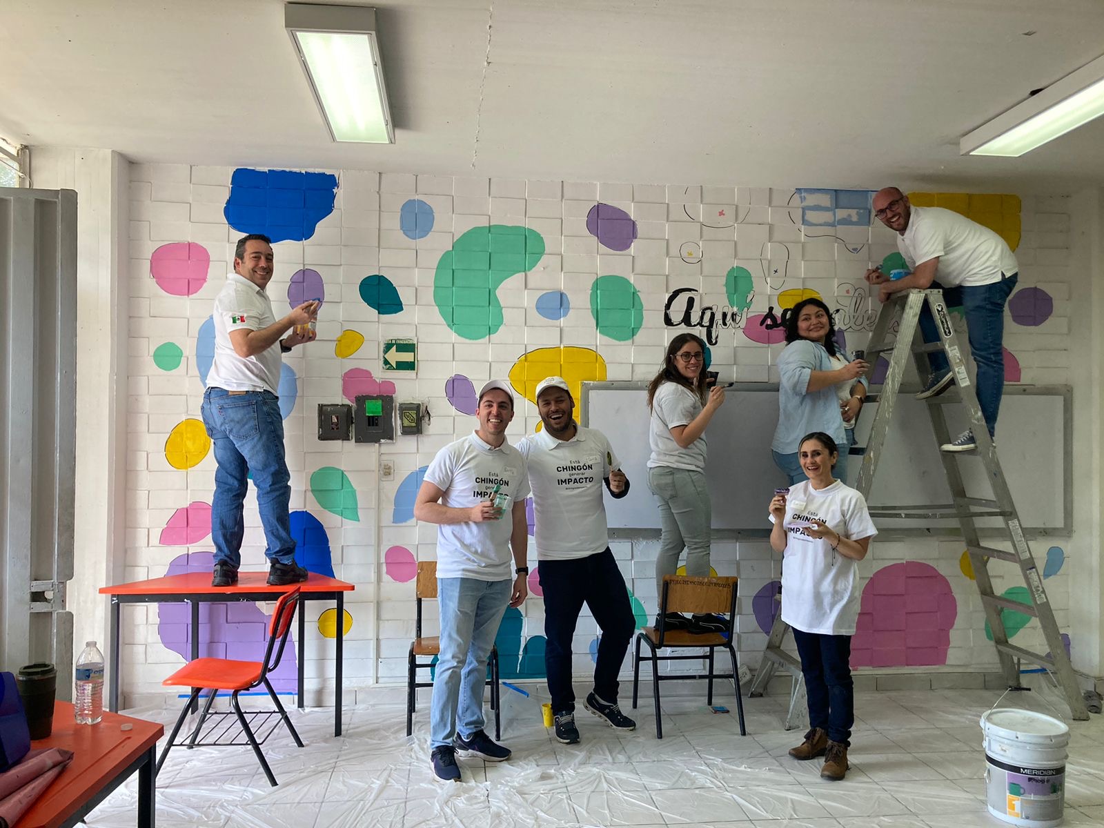 Voluntarios pintando un mural de colores en una escuela